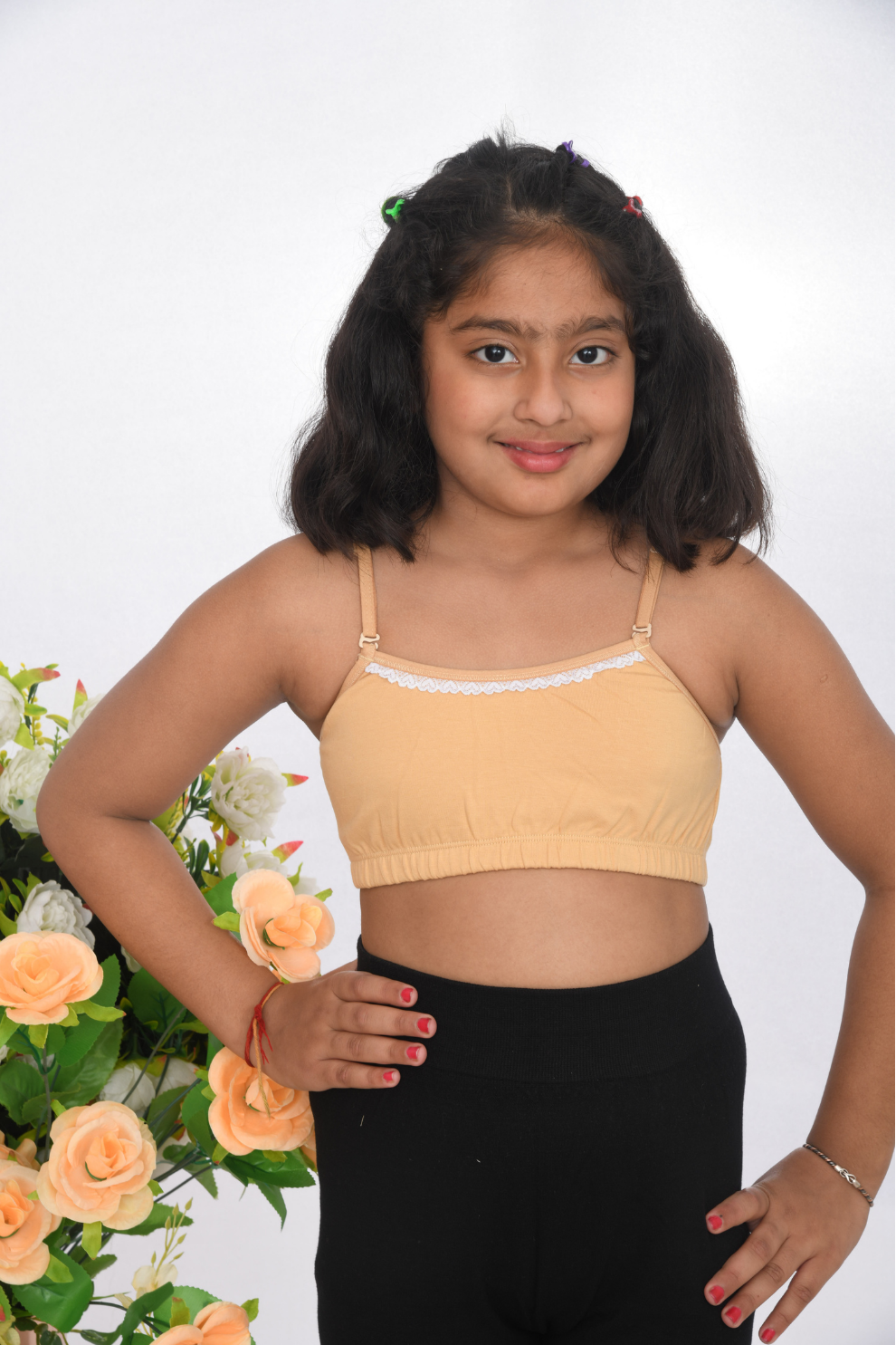 A young girl wearing a beige training bra with lace design, adjustable straps, and a tag-free finish front view