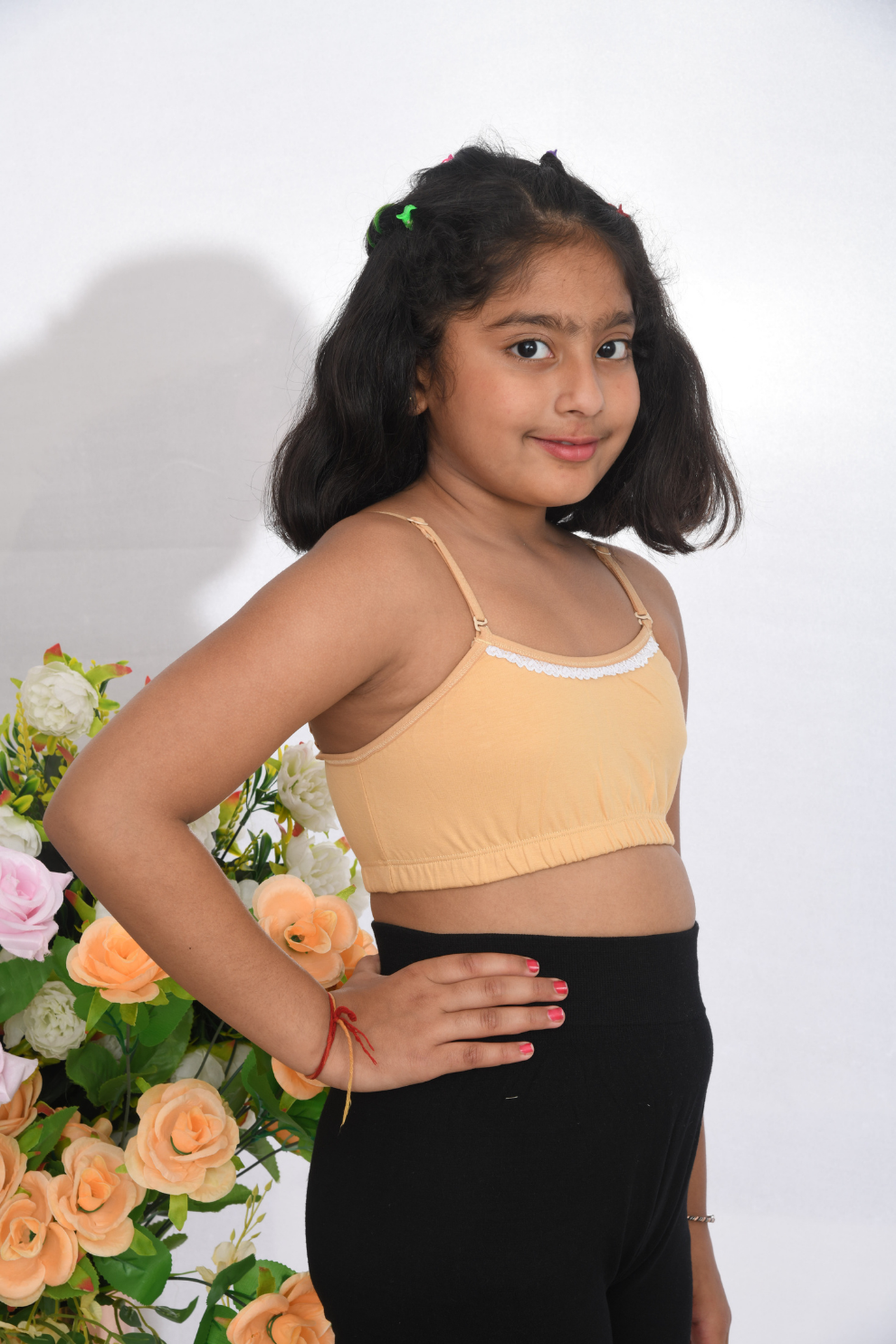 A young girl wearing a beige training bra with lace design, adjustable straps, and a tag-free finish side view