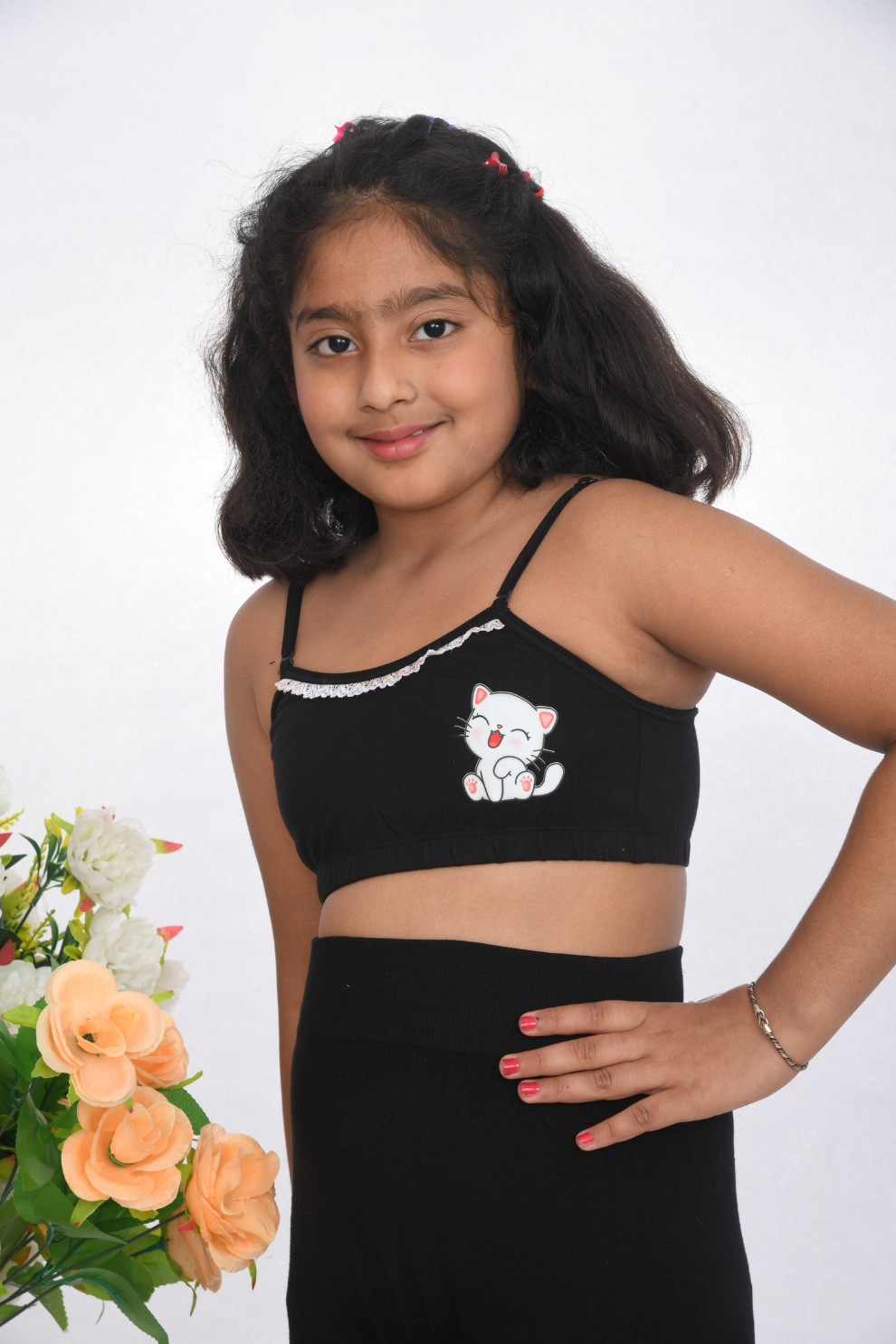 A young girl wearing a black training bra with delicate lace detailing, side view design, and adjustable straps.