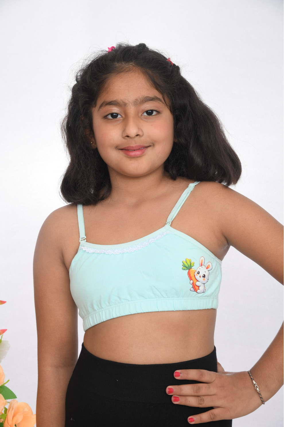 A young girl wearing a sea green training bra with lace detailing, front view, adjustable straps.
