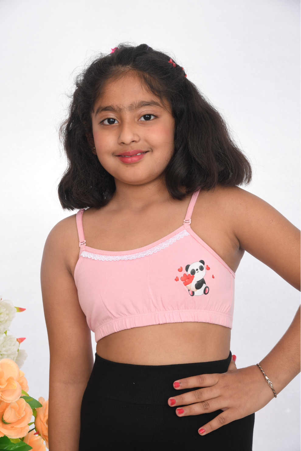 A teen girl wearing a pink training bra with lace detailing, front view, adjustable straps.
