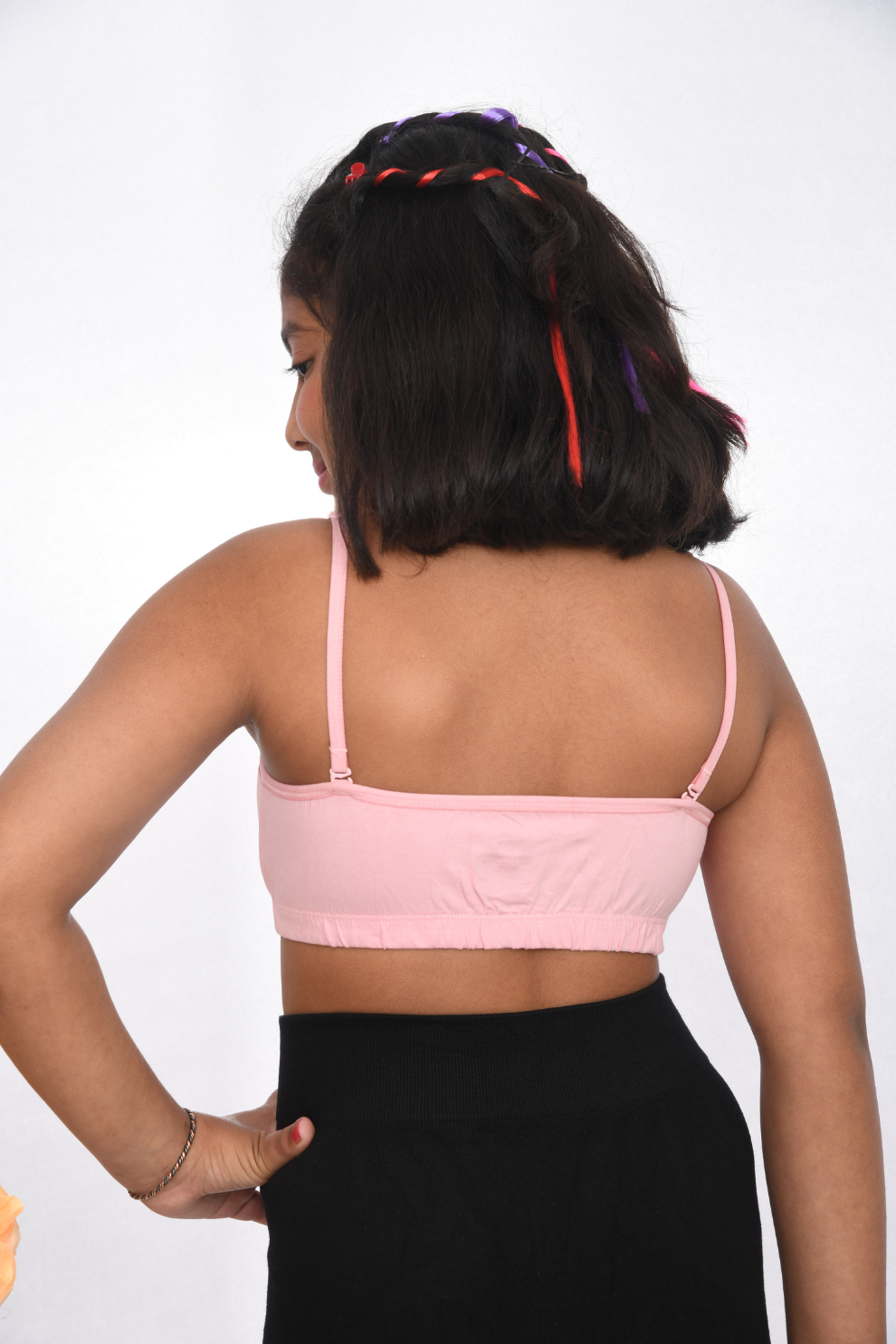 Teen Pre-teen girl wearing a pink training bra with lace detailing, back view, adjustable straps.